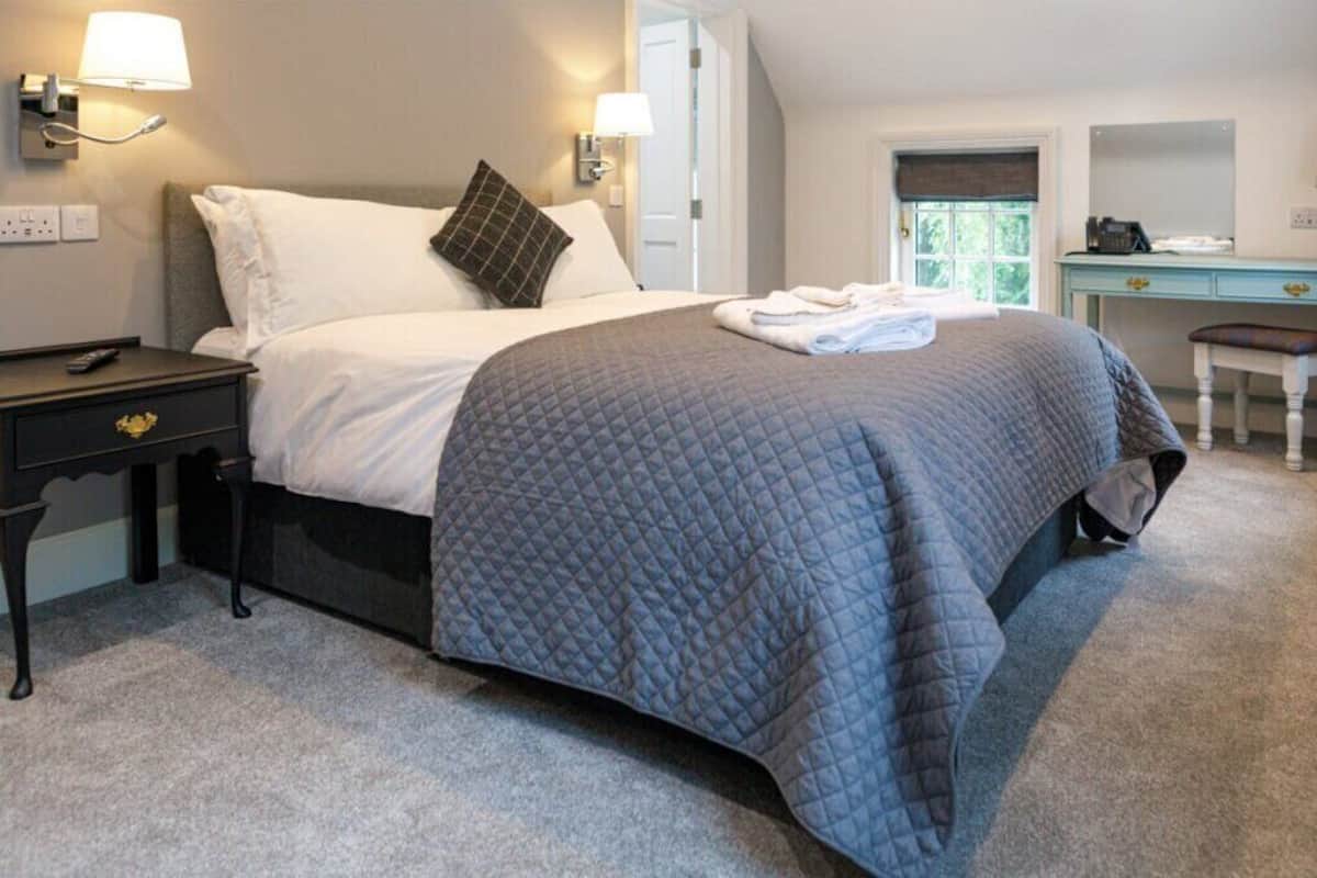 Ein ordentlich eingerichtetes Schlafzimmer mit Bett, Nachttischen, Schreibtisch und Stuhl.