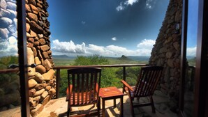 Ein Balkon mit Steinwänden, zwei Holzstühlen und einem Tisch.