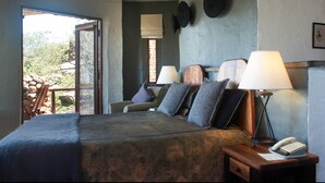 Ein Schlafzimmer mit Bett, Nachttischlampen, einem Nachttisch mit Telefon und einem Fenster mit Blick ins Freie.