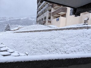Schneeverdeckte Landschaft mit einem Gebäude, das Balkone und eine Steinmauer hat.
