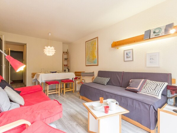 Relax in this stylish living space with a comfortable sofa, dining table, and artwork-adorned walls.