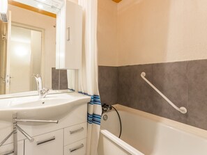 Bathroom features a sink, bathtub, and mirror, with a towel rack and door to another room.