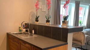 A kitchen with a large island, wooden cabinets, a sink, and three potted orchids on the countertop. - Notodden Sentrum Apartment NO 8 (Notodden)