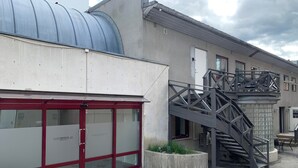 A building with a red-framed entrance, a metal staircase, and a large blue roof structure. - Notodden Sentrum Apartment NO 8 (Notodden)