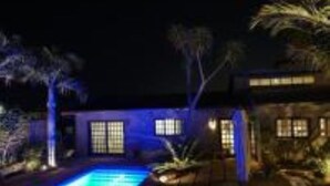 Une vue nocturne d’une maison avec une piscine, une terrasse et un jardin.