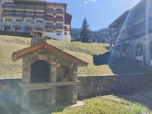Ein Steinhaus mit geneigtem Dach, möglicherweise eine kleine Kapelle oder ein Gästehaus, mit einer Mauer davor.