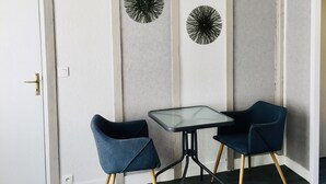Ein Zimmer mit weißer Tür, einem kleinen Tisch und zwei Stühlen, sowie Wanddekoration.