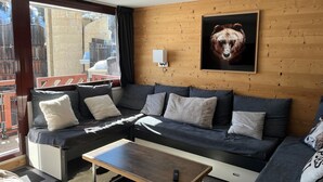 Un salon moderne avec un canapé, une table basse et une œuvre d’art sur le thème des ours accrochée au mur.