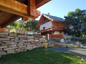 A traditional wooden house with a stone wall and a sloped roof.