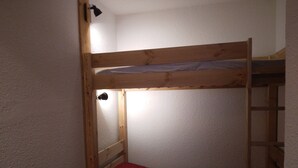 A bunk bed with a red mattress and a wooden ladder. - Bright divisible studio, direct piste access, balcony, pets allowed (Plagne Bellecôte)