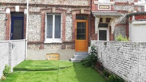 Una casa adosada de dos plantas con un jardín delantero cuidado y fachada de ladrillo.