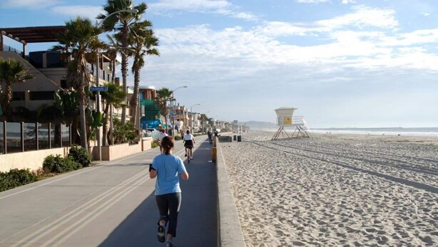 A beachside walkway with palm trees, a lifeguard tower, and a clear sky. - Two Bedroom Beach Cottage in Pacific Beach, San Diego (San Diego)