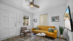 A living room with a sofa, armchair, coffee table, and a ceiling fan. - Two Bedroom Beach Cottage in Pacific Beach, San Diego (San Diego)