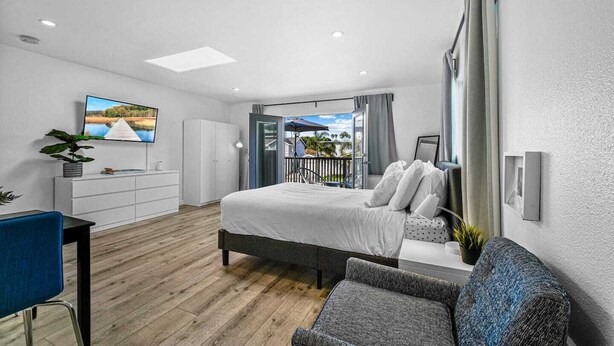 A modern bedroom with a large bed, a desk, and a balcony with a view. - Studio Beach Rental in Pacific Beach, San Diego (San Diego)