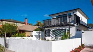A modern two-story house with a balcony, white exterior walls, and a gated entrance. - Studio Beach Rental in Pacific Beach, San Diego (San Diego)