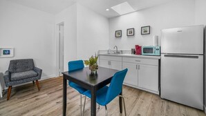 A compact kitchen with a refrigerator, microwave, and sink. There is a dining table with two chairs and a small plant on it. - Studio Beach Rental in Pacific Beach, San Diego (San Diego)