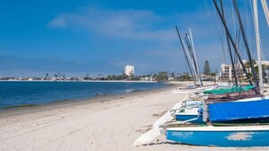 A beach with boats lined up on the sand, a clear sky, and buildings in the background. - Studio Beach Rental in Pacific Beach, San Diego (San Diego)