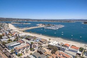 Vue aérienne d’une ville côtière avec un port de plaisance, des plages de sable et des immeubles résidentiels.