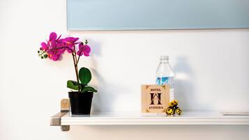 A shelf with a potted orchid, a water bottle, a hotel sign, and a small toy bicycle.