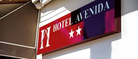 Un letrero de hotel con el nombre 'HOTEL AVENIDA' y tres estrellas.