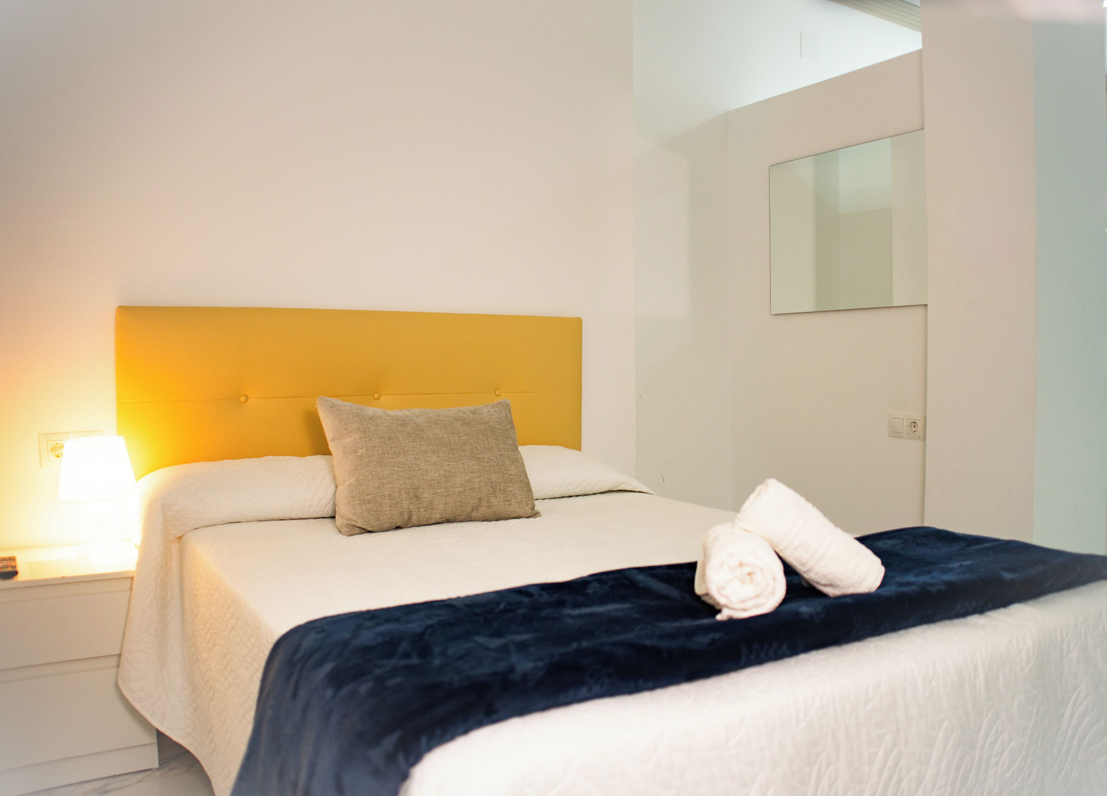 Una camera d'albergo con un letto, un comodino, una lampada e un armadio.