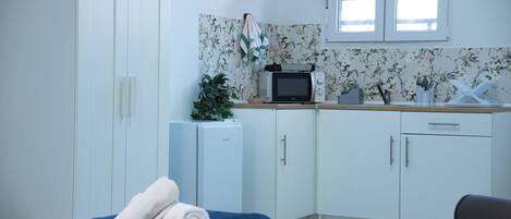 A hotel room with a bed, a small kitchenette, and a window.