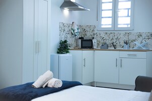 A hotel room with a bed, a small kitchenette, and a window.