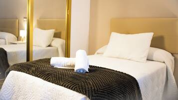 A hotel room with a bed, a bedside table, a mirror, and a window.
