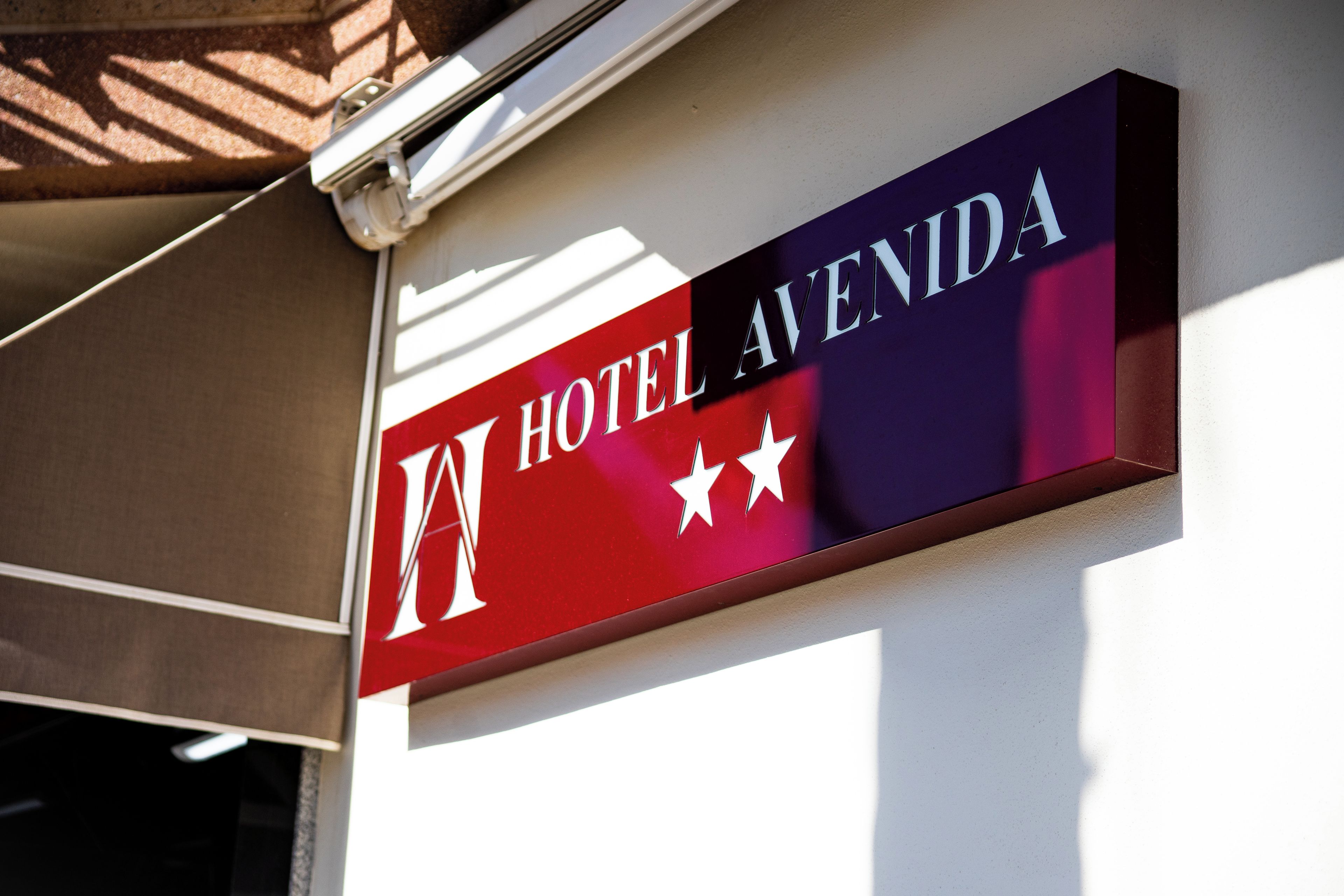 A hotel sign with the name 'HOTEL AVENIDA' and three stars.