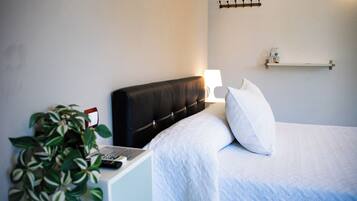 Ein ordentlich bezogenes Bett mit weißer Bettwäsche, einem schwarzen Kopfteil und einer Nachttischlampe.