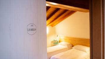 A room with two beds, a wooden ceiling, and a sign on the wall.
