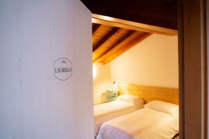 Una habitación con dos camas, techo de madera y un letrero en la pared.