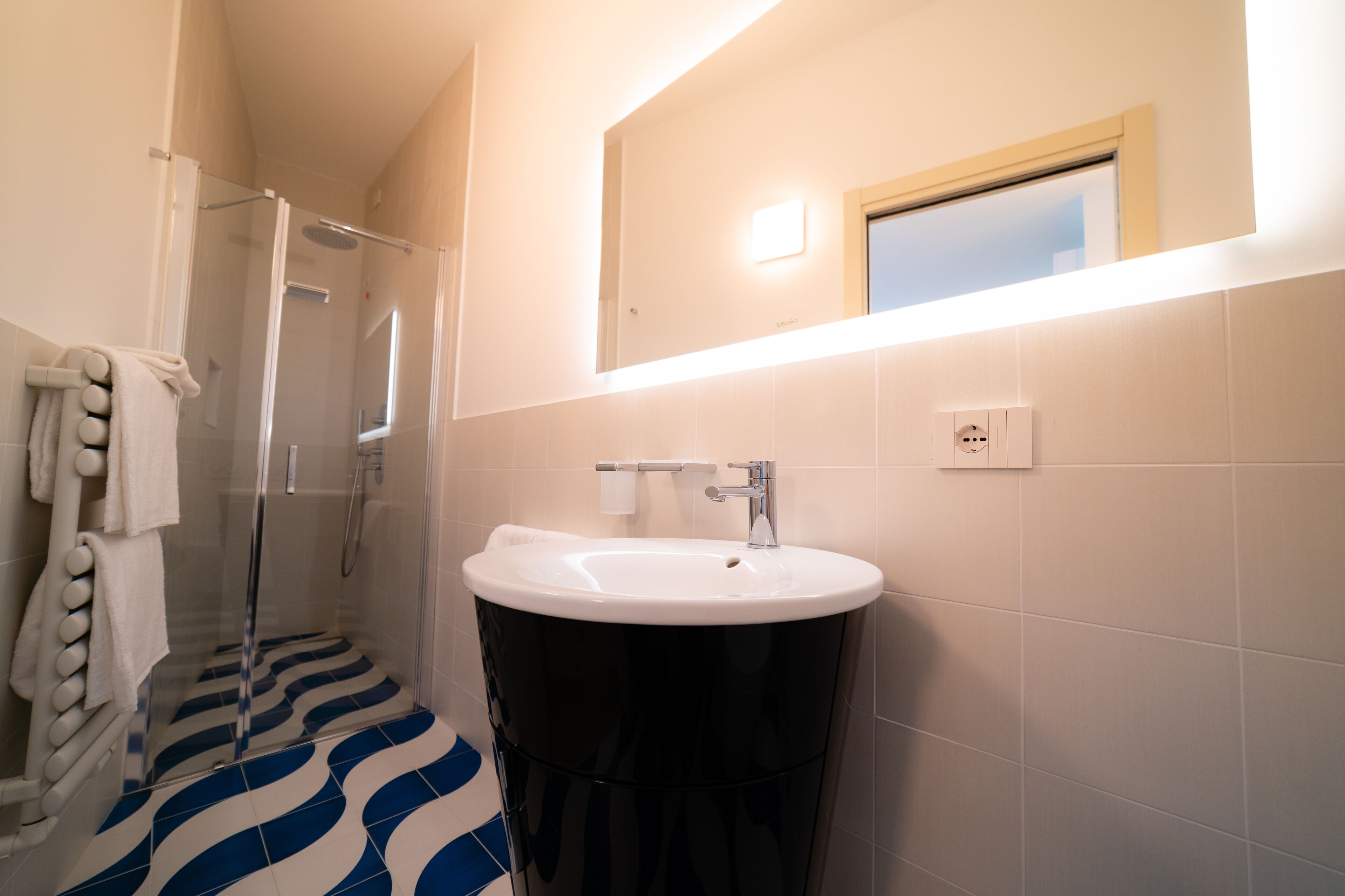 Un bagno con doccia, lavandino e specchio.
