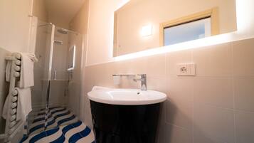 Un bagno con doccia, lavandino e specchio.