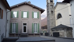 A building with a central entrance, green shutters, and a bell tower. - Locanda Alberti (Mandello del Lario)