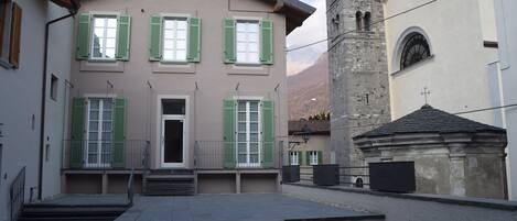 A building with a central entrance, green shutters, and a bell tower.
