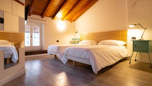 A bedroom with two beds, wooden flooring, and a wooden ceiling. - Locanda Alberti (Mandello del Lario)