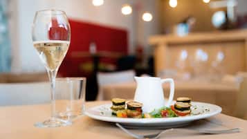 A dining table with a plate of vegetable terrines, a glass of white wine, and a white pitcher.