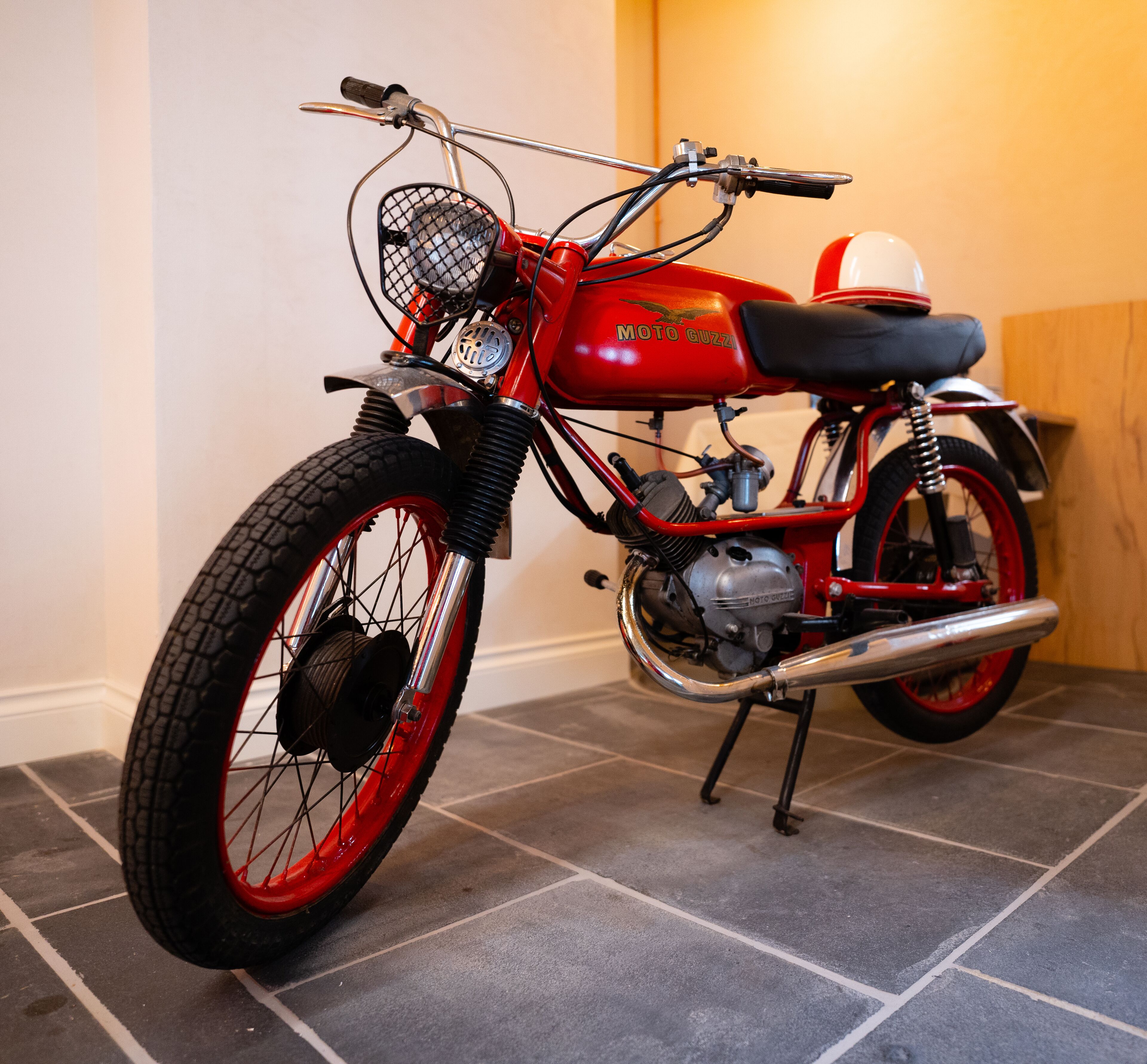 Ein Motorrad im Vintage-Stil mit rotschwarzer Farbgebung, einem Korb vorne und einem Sitz mit schwarzem Bezug.
