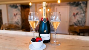 A bottle of Bollinger champagne, two glasses of champagne, and a bowl of fruit on a wooden table. - Locanda Alberti (Mandello del Lario)