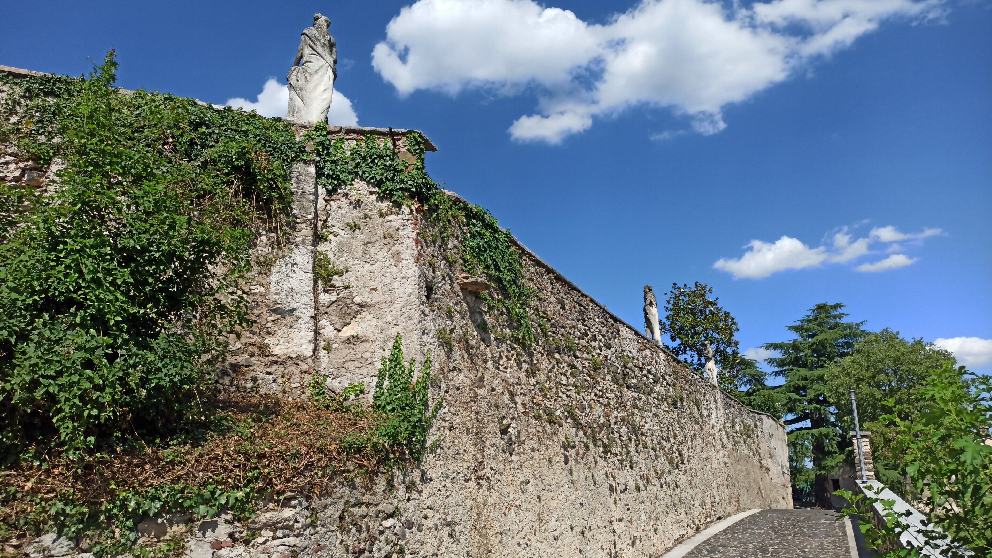 Mural de pedra com estátuas e vegetação.