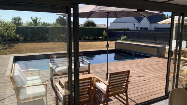 Ein überdachter Außenbereich mit Pool, Holzterrasse und Sitzgelegenheiten.