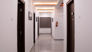 A modern hallway with white walls, dark doors, and orange accents on the ceiling.