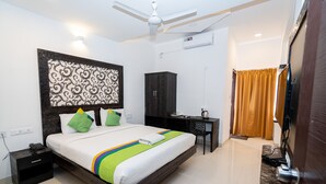 A hotel room with a bed, a desk, a wardrobe, and a ceiling fan.