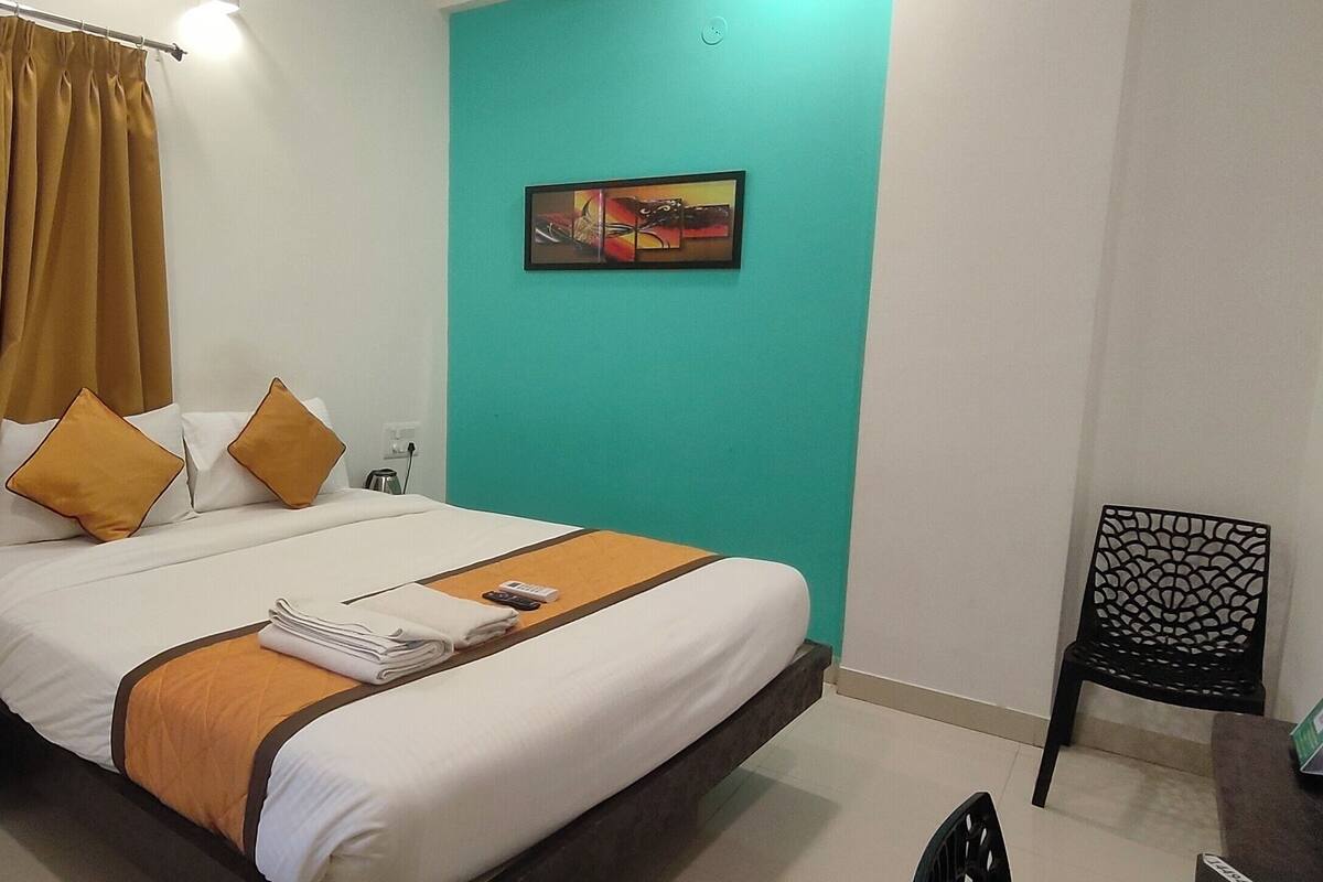 Une chambre d’hôtel avec un lit, une table de chevet, une chaise et un tableau au mur.