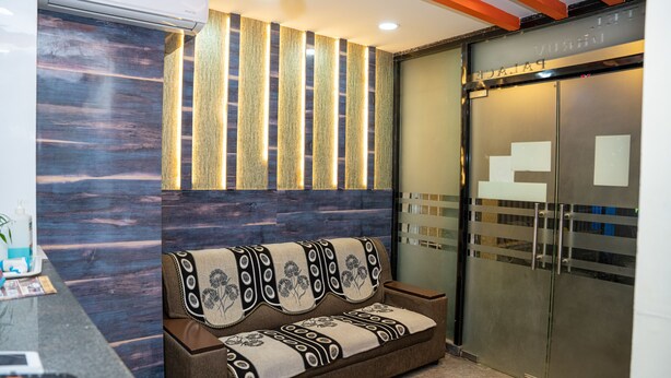 A reception area with a sofa, a reception desk, and a glass door leading to a staircase.