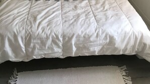 A neatly made bed with striped pillows and a white duvet, a small bedside table with a lamp, and a wall-mounted picture. - Seasonal rental (Les Mathes)