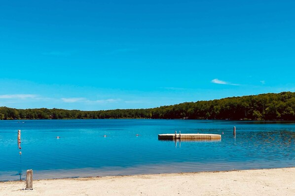 En klar sjö med en sandstrand och en brygga.