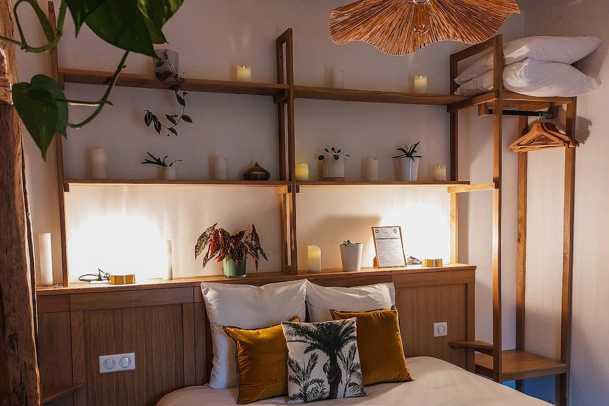 Un dormitorio con cama, estantes de madera y una lámpara colgante.
