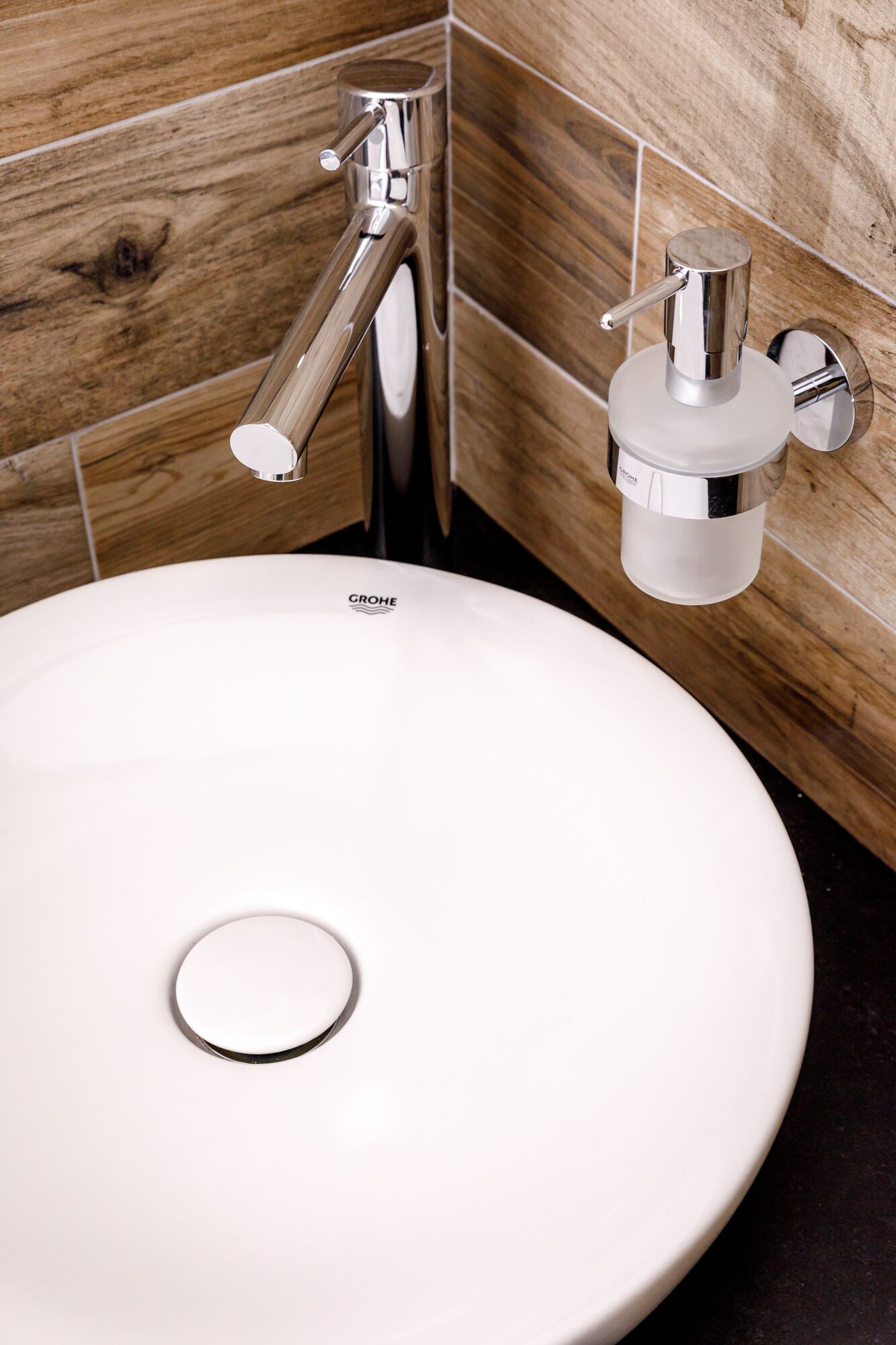 A white bathroom sink with a GROHE faucet and soap dispenser.